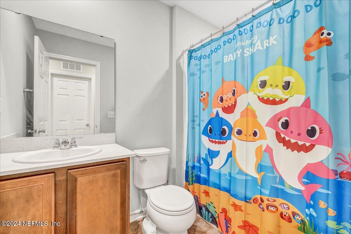 183 Silver Fern Drive St. Augustine, FL 32086 - Photo 25 of 29 a bathroom with a sink and mirror with toilet