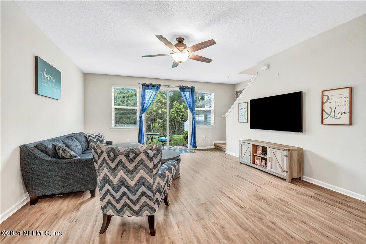 183 Silver Fern Drive St. Augustine, FL 32086 - Photo 10 of 29 a living room with furniture a flat screen tv and a floor to ceiling window