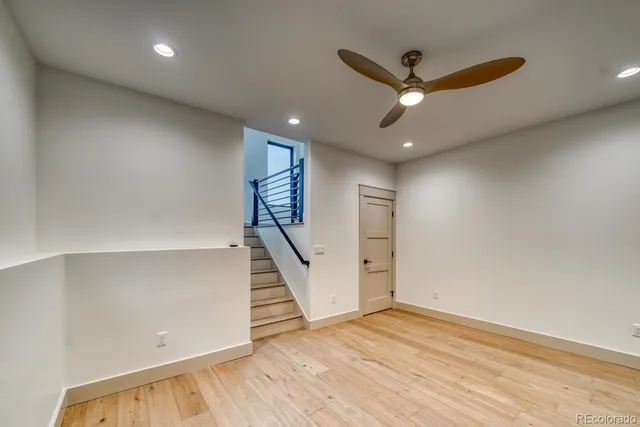 a view of an empty room with wooden floor and a ceiling fan