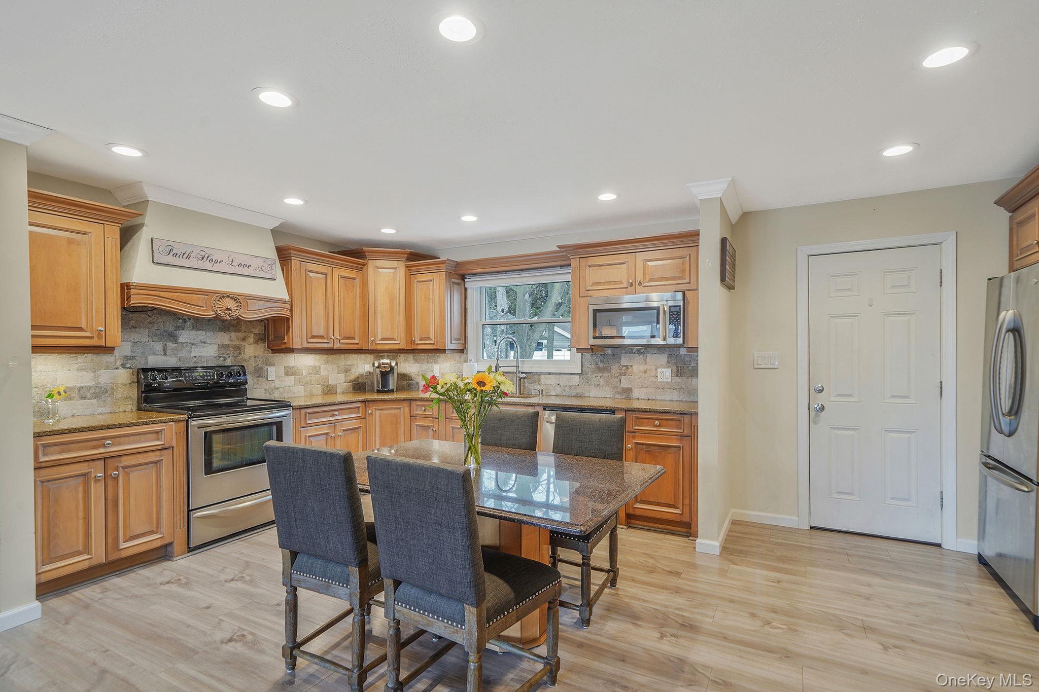11 Nehring Avenue Babylon, NY 11702 - Photo 8 of 27 a kitchen with stainless steel appliances granite countertop a dining table chairs refrigerator and microwave