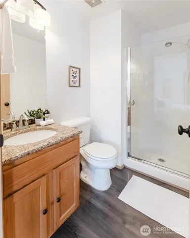 a bathroom with a granite countertop sink toilet a mirror and shower