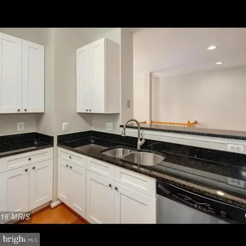 a kitchen with granite countertop a sink and white cabinets