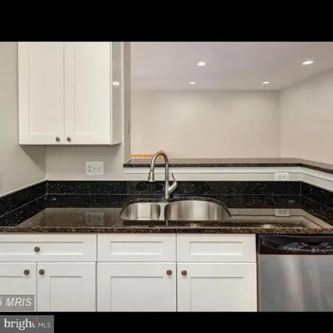 a kitchen with white cabinets and sink