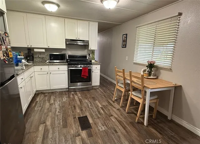 a kitchen with granite countertop a stove and white cabinets