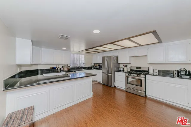 a kitchen with granite countertop a sink cabinets stainless steel appliances and wooden floor