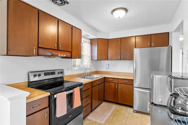 a kitchen with stainless steel appliances granite countertop a refrigerator a sink dishwasher a stove with wooden cabinets