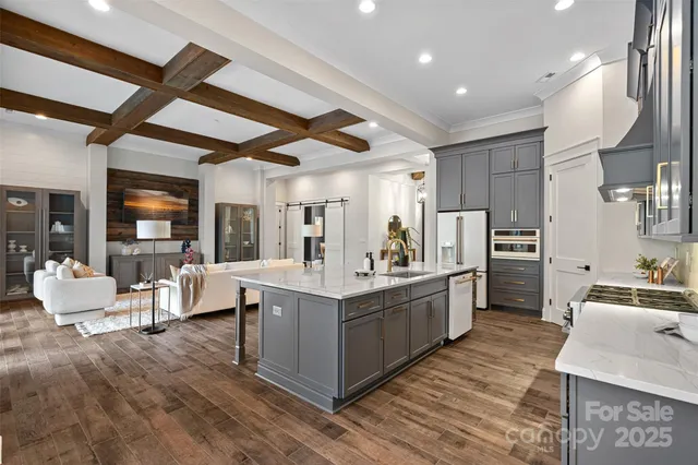 a large kitchen with stainless steel appliances kitchen island granite countertop a large kitchen island a stove a refrigerator a sink dishwasher a dining table and chairs with wooden floor