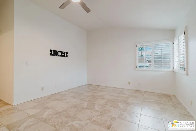 an empty room with windows and fan view