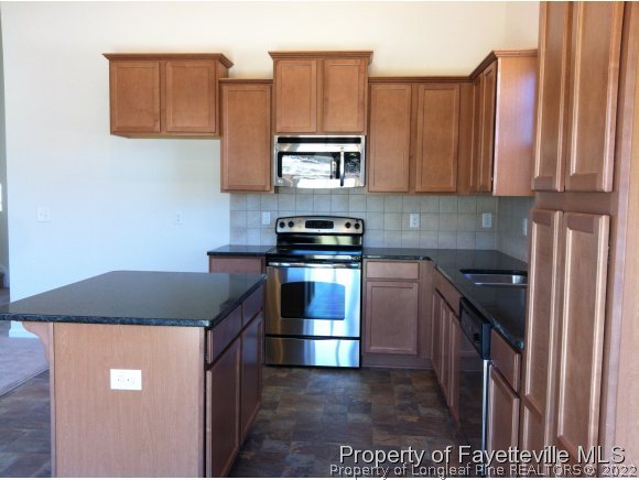 360 River Oak Street Spring Lake, NC 28390 - Photo 6 of 15 a kitchen with stainless steel appliances granite countertop a stove a refrigerator and a microwave