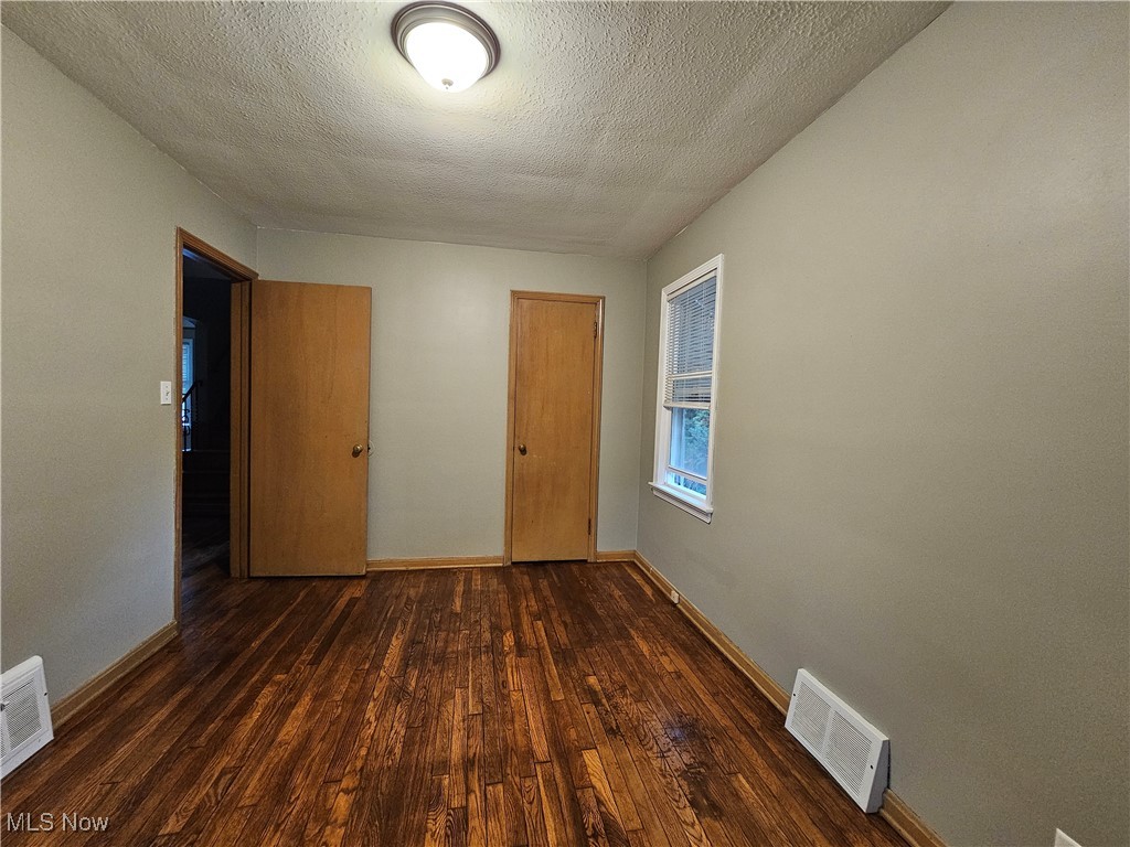 13514 Granger Road Cleveland, OH 44125 - Photo 13 of 23 Empty room with a textured ceiling and dark hardwood / wood-style flooring