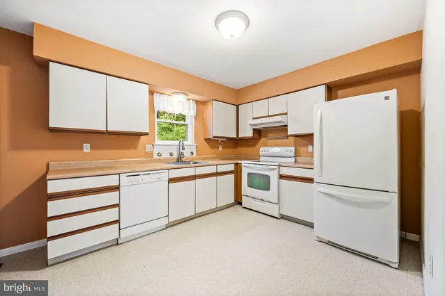 a kitchen with granite countertop white cabinets and white appliances
