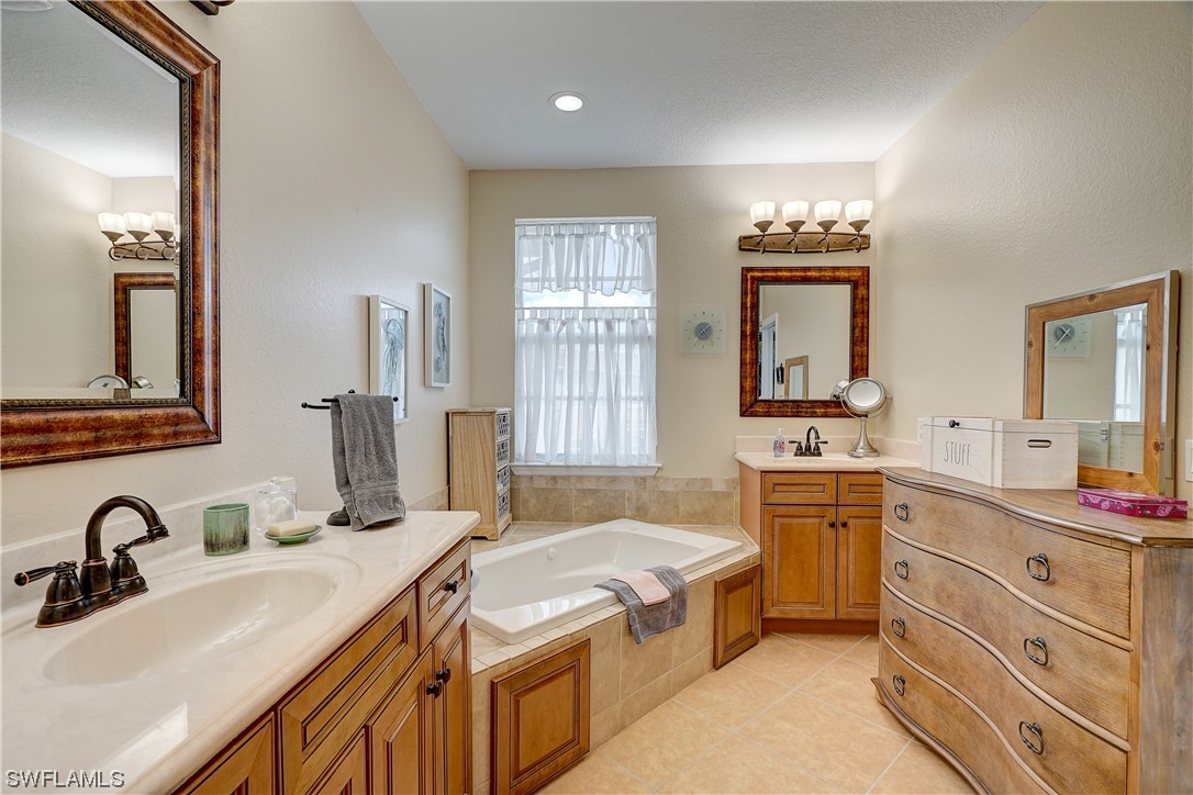 4089 Cherrybrook Loop Fort Myers, FL 33966 - Photo 20 of 35 a bathroom with a granite countertop double vanity sink a mirror and a bathtub
