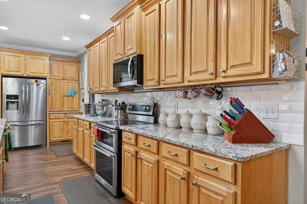 281 Jule Ingram Road Milledgeville, GA 31061 - Photo 9 of 79 a kitchen with stainless steel appliances granite countertop a refrigerator a sink dishwasher and white cabinets with wooden floor