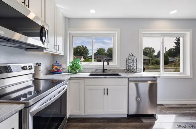 a kitchen with stainless steel appliances granite countertop a sink and a white cabinets