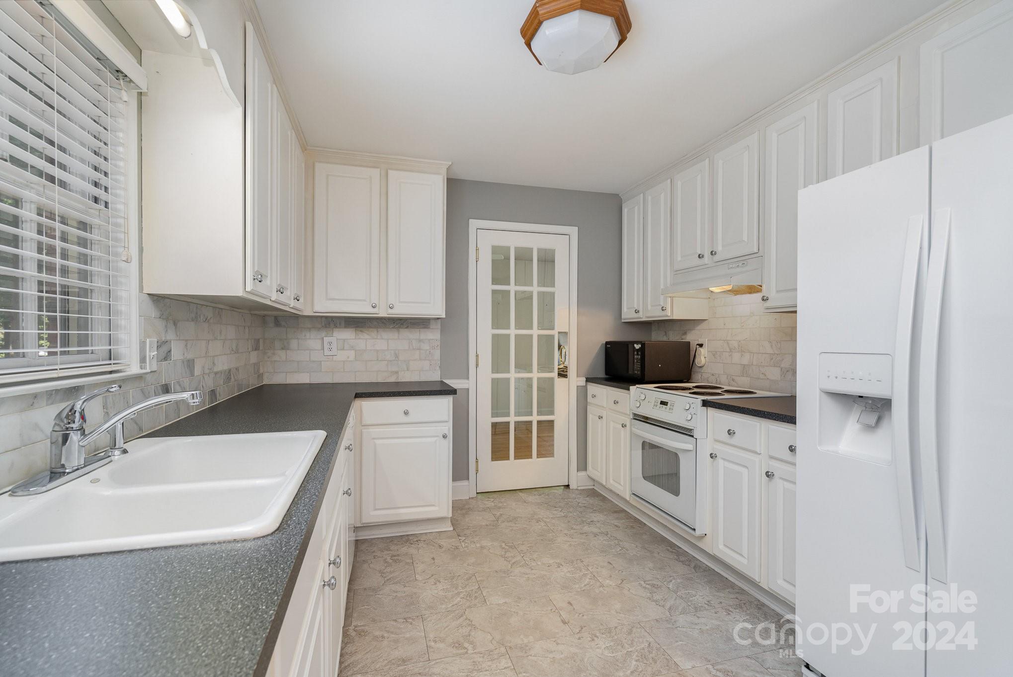 6529 Idlebrook Drive Charlotte, NC 28212 - Photo 16 of 28 a kitchen with white cabinets and white appliances