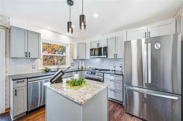 a kitchen with kitchen island stainless steel appliances a sink stove and refrigerator