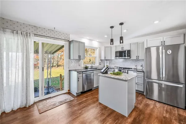 a kitchen with granite countertop stainless steel appliances a counter top space and a large window