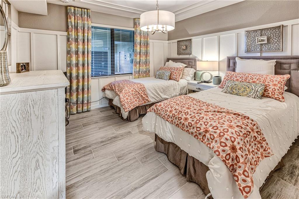 9572 Trevi Court, Unit 5015 Naples, FL 34113 - Photo 14 of 39 a bedroom with two beds and a chandelier