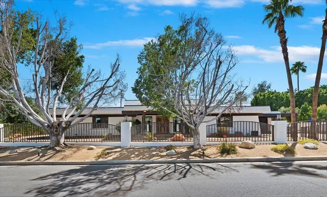 a front view of a house with street view and trees