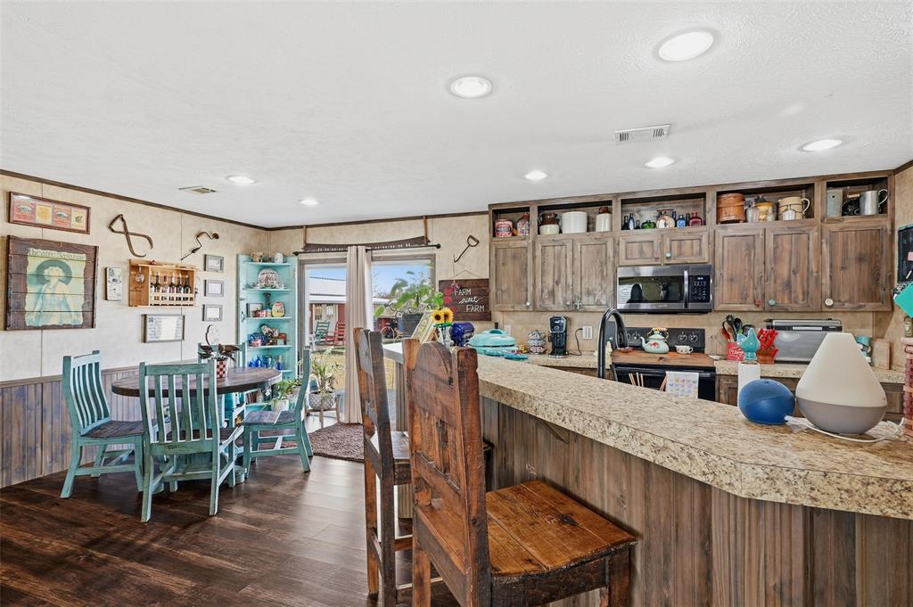 1949 Greer Road Sadler, TX 76264 - Photo 12 of 39 a kitchen with stainless steel appliances kitchen island granite countertop a table chairs in it and wooden floors