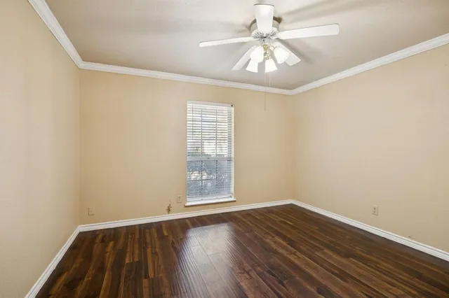 an empty room with wooden floor chandelier fan and windows