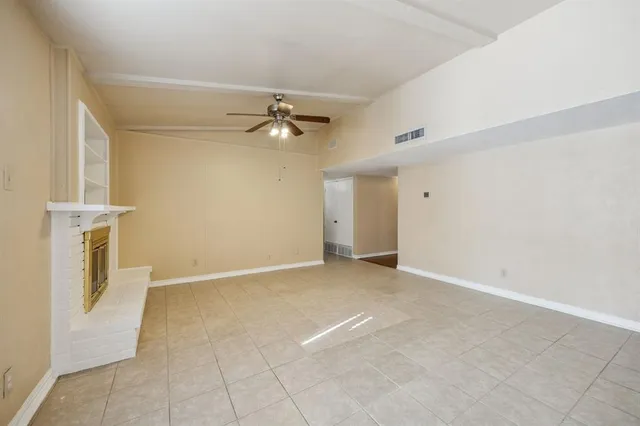 a view of an empty room with a chandelier fan