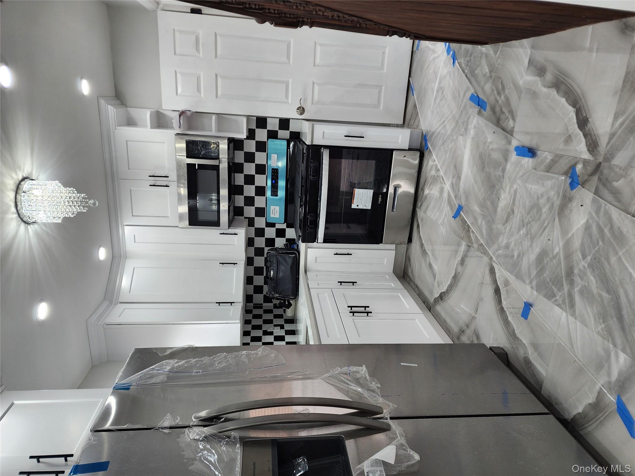 224-06 114th Road Queens, NY 11411 - Photo 3 of 15 Kitchen featuring refrigerator, stainless steel gas range oven, decorative backsplash, white cabinetry, and light marble finish floors