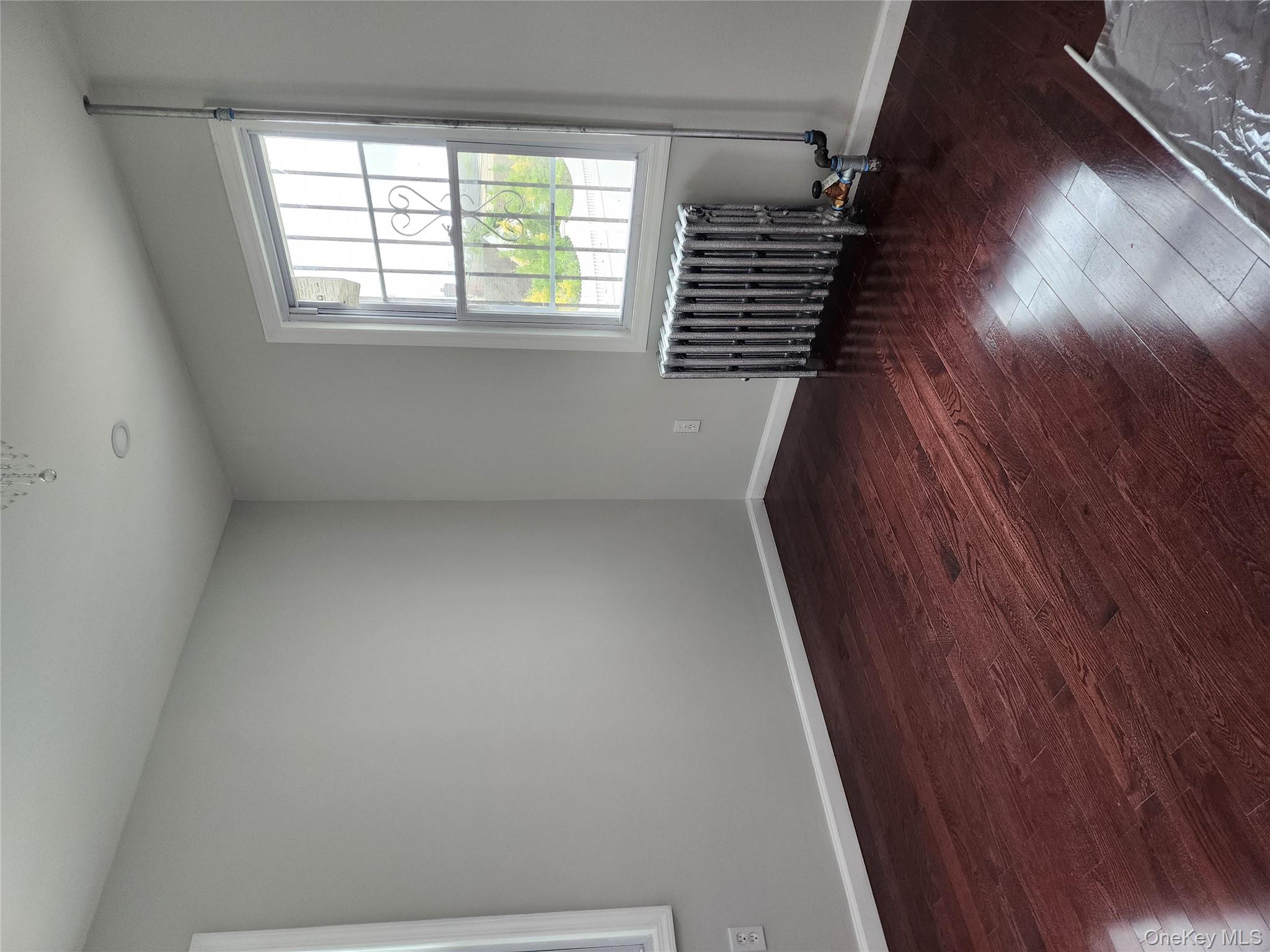 224-06 114th Road Queens, NY 11411 - Photo 6 of 15 Unfurnished room featuring radiator, wood-type flooring, and baseboards