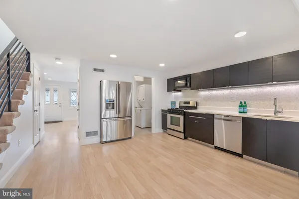 a kitchen with stainless steel appliances kitchen island granite countertop a refrigerator a sink a stove and oven with wooden floor