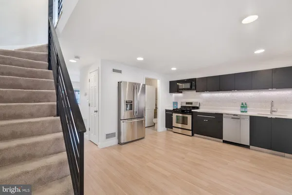 a kitchen with stainless steel appliances kitchen island granite countertop a refrigerator a sink a stove and oven