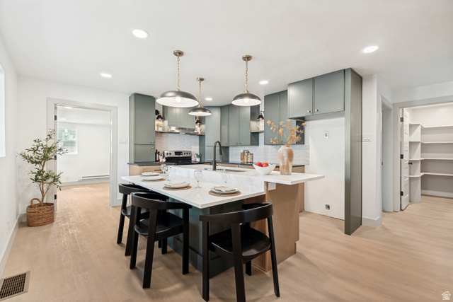 1010 West Maple Street Mapleton, UT 84664 - Photo 6 of 24 Modern kitchen featuring a central island with seating, pendant lighting, light wood-finish flooring, and a pantry with built-in shelving
