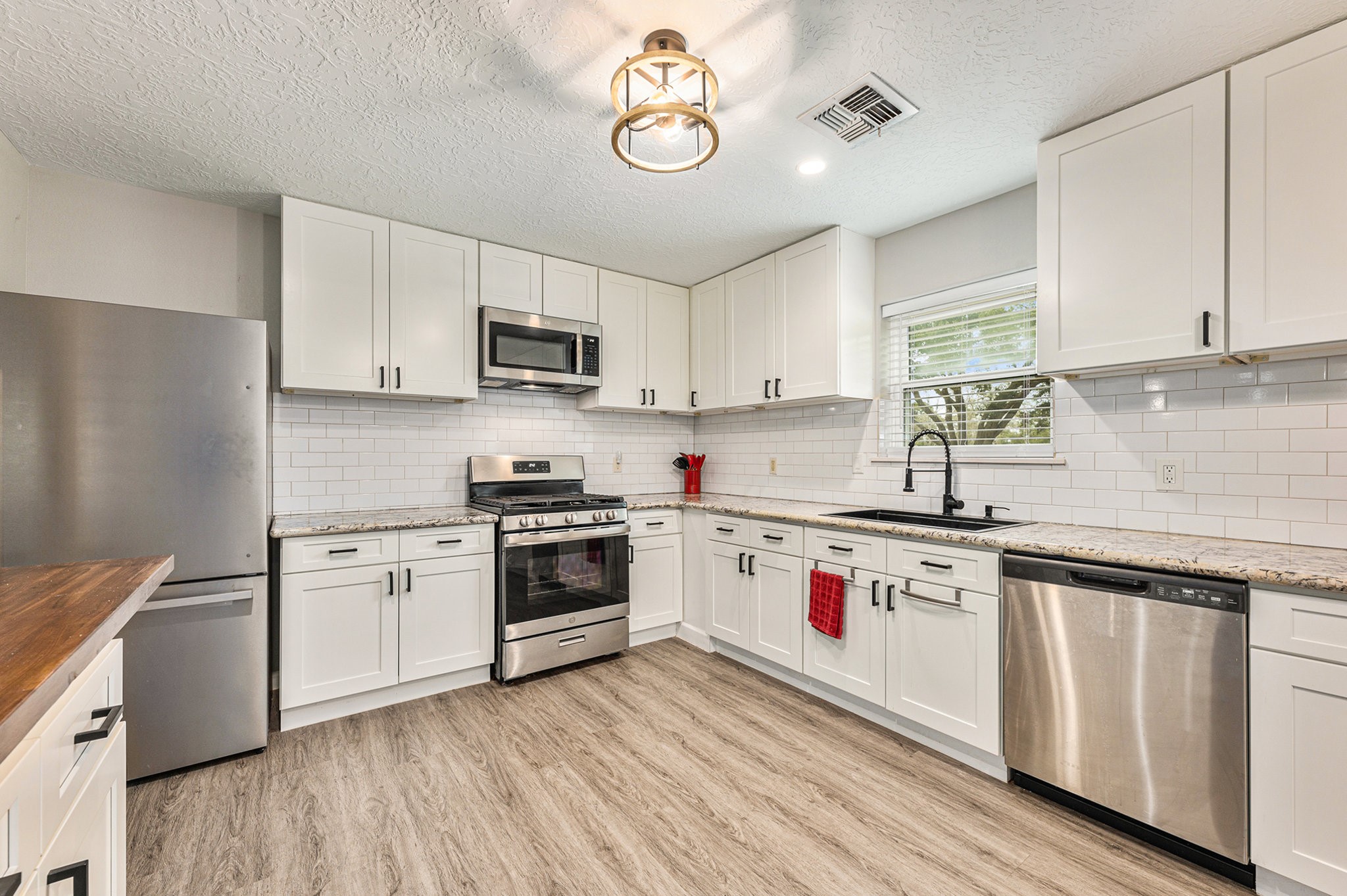 1906 12th Street Hempstead, TX 77445 - Photo 13 of 32 a kitchen with granite countertop a stove top oven sink and cabinets