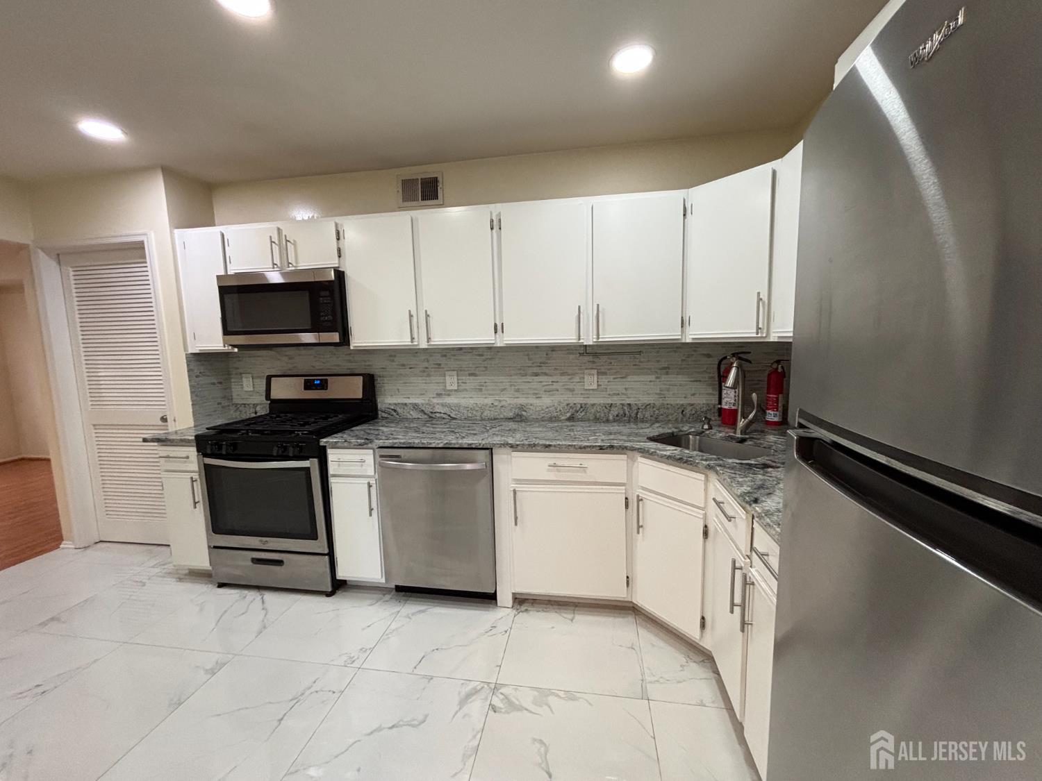 1301 Plymouth Road North Brunswick, NJ 08902 - Photo 5 of 21 a kitchen with stainless steel appliances granite countertop a stove a sink and a microwave