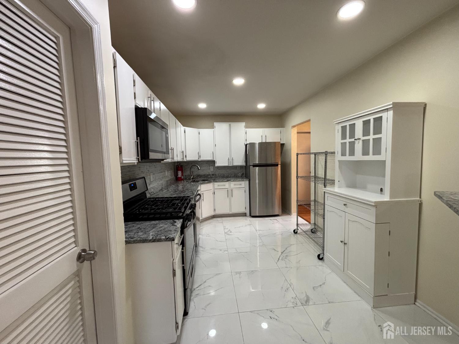 1301 Plymouth Road North Brunswick, NJ 08902 - Photo 7 of 21 a kitchen with white cabinets and stainless steel appliances