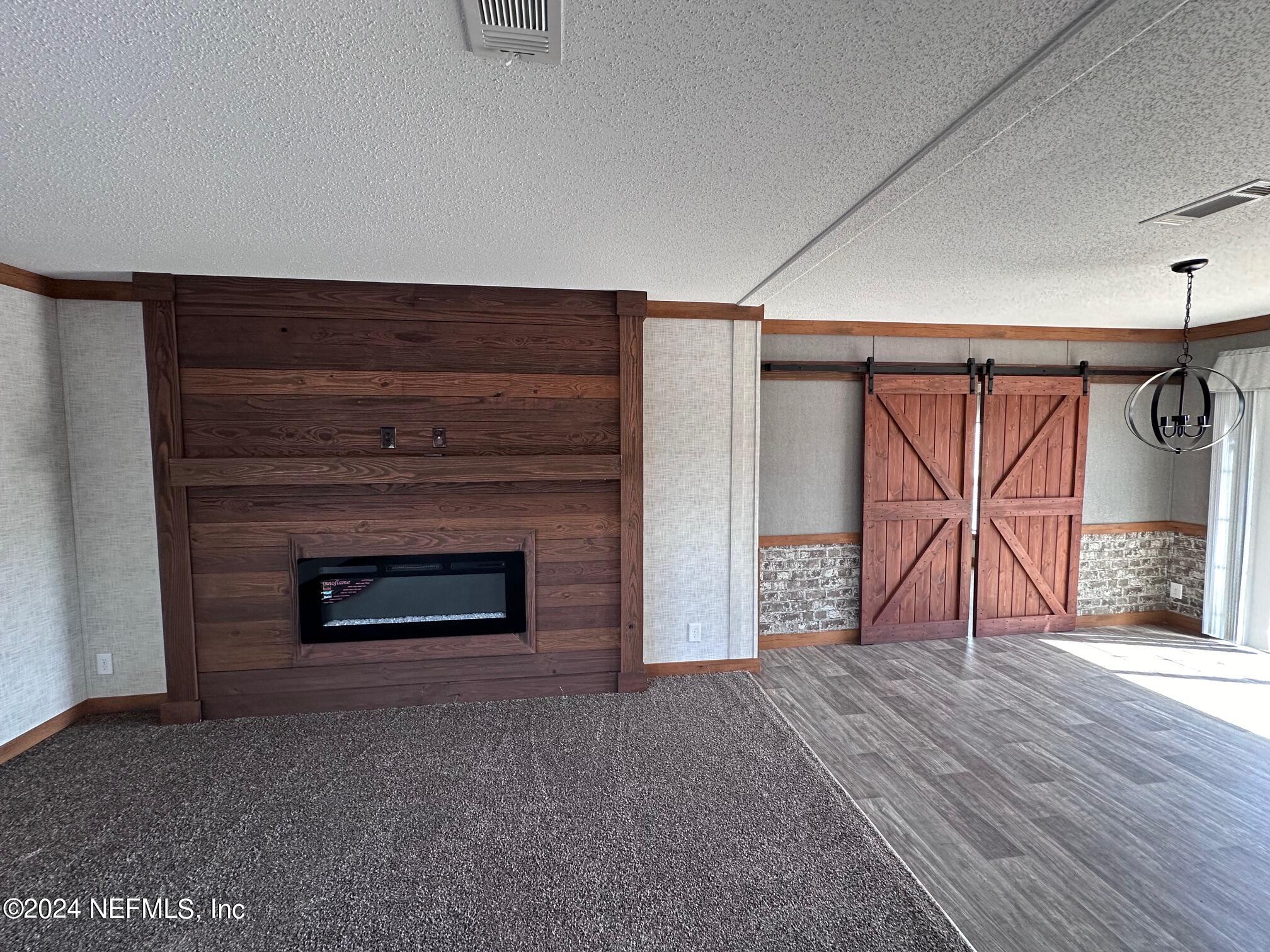 8682 Noah Davis Road Glen St. Mary, FL 32040 - Photo 4 of 19 a view of an empty room with wooden floor fireplace and a window