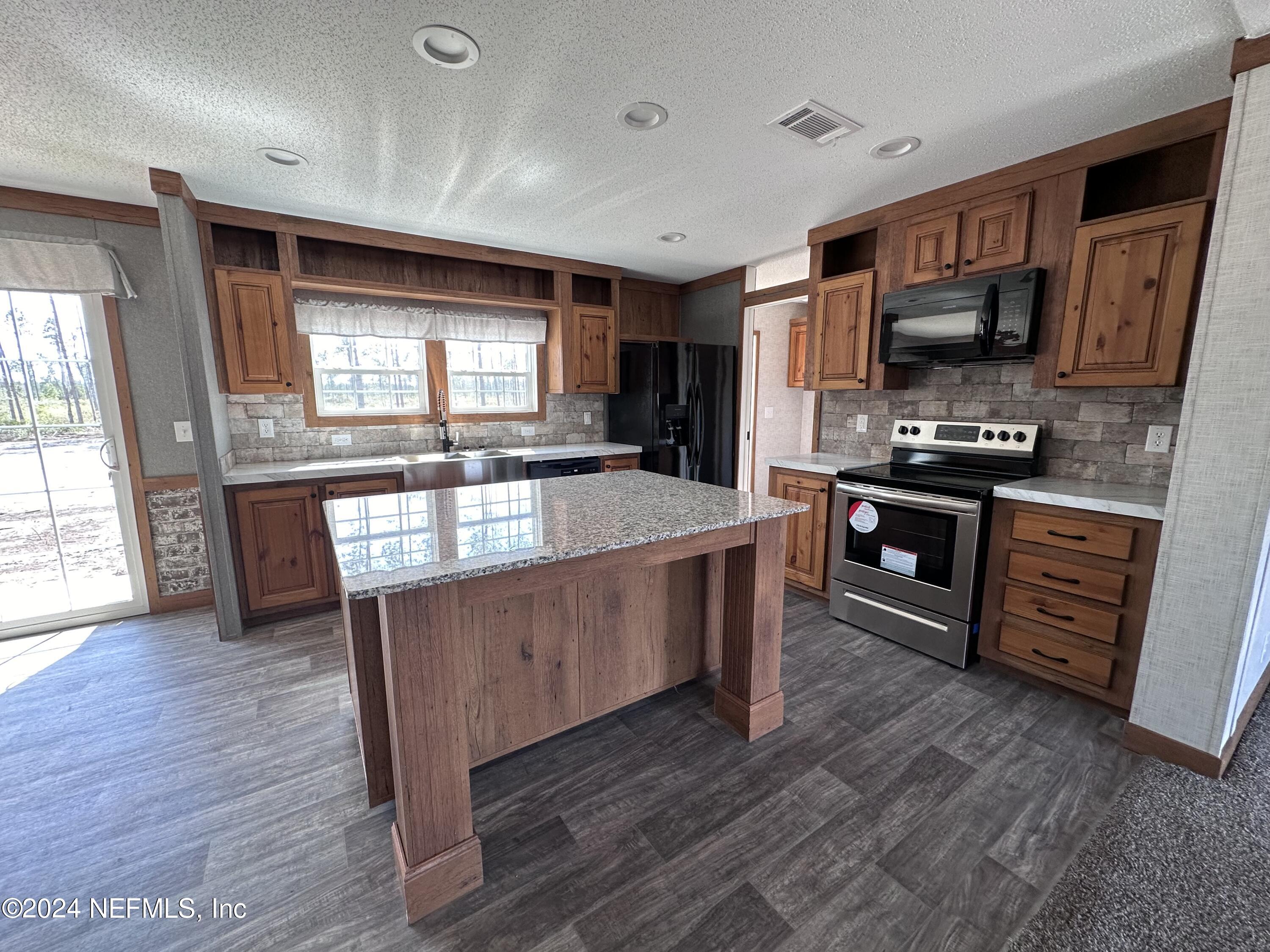 8682 Noah Davis Road Glen St. Mary, FL 32040 - Photo 6 of 19 a kitchen with stainless steel appliances granite countertop a stove a sink and a refrigerator