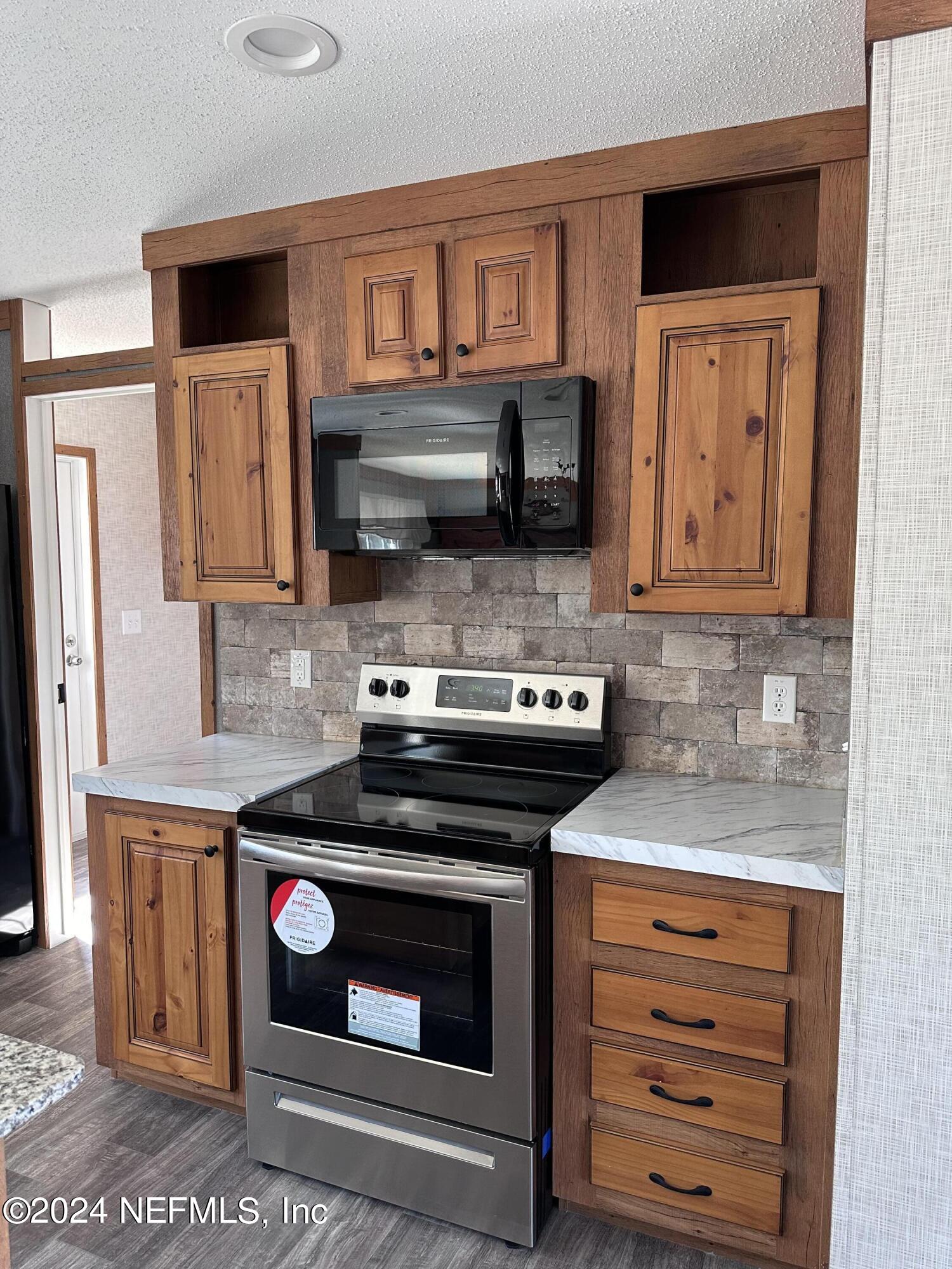 8682 Noah Davis Road Glen St. Mary, FL 32040 - Photo 7 of 19 a kitchen with stainless steel appliances granite countertop a stove a microwave and a sink