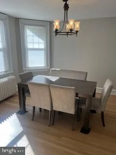 a dining room with wooden floor a chandelier a wooden table and chairs