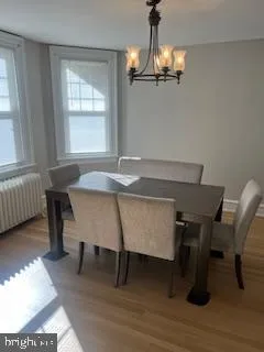 a dining room with wooden floor a chandelier a wooden table and chairs