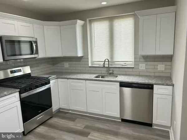 a kitchen with granite countertop white cabinets stainless steel appliances and a sink