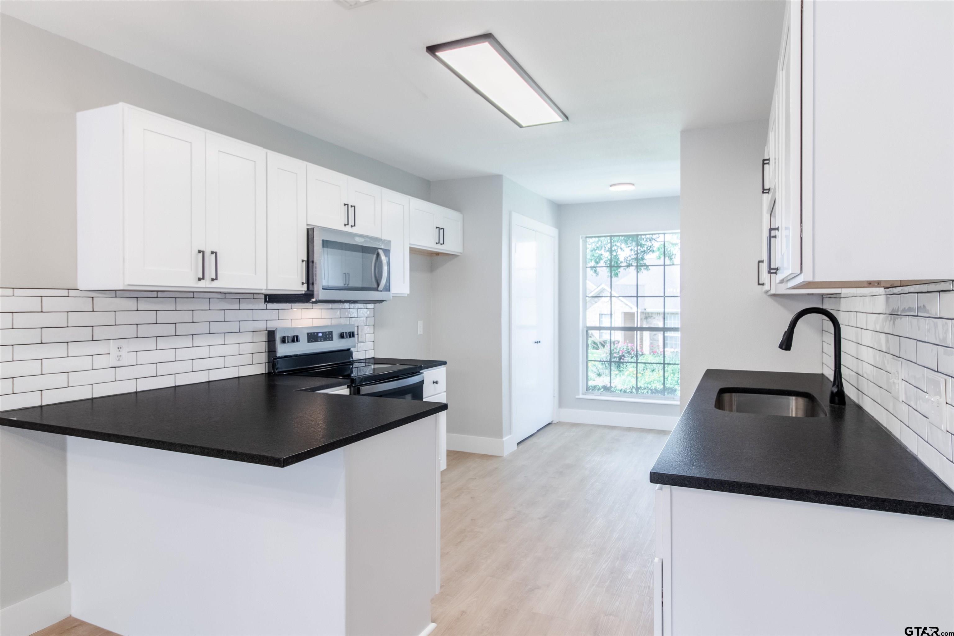 415 Thigpen Drive Tyler, TX 75703 - Photo 9 of 32 a kitchen with granite countertop a sink and a stove top oven with wooden floor