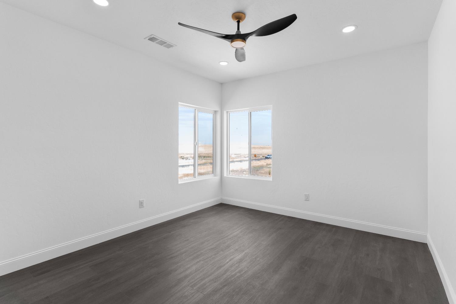 36950 Pauline Avenue Madera, CA 93636 - Photo 20 of 48 an empty room with wooden floor ceiling fan and windows