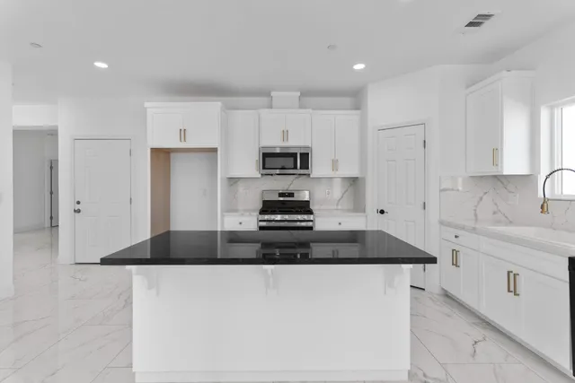 a kitchen with granite countertop white cabinets and stainless steel appliances
