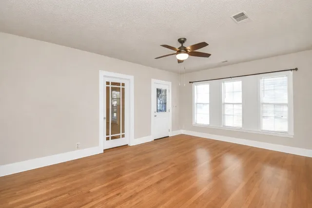 a view of an empty room with a window and a kitchen