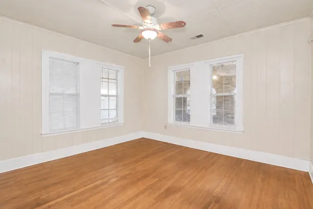 a view of an empty room with a window and wooden floor