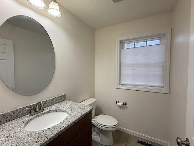 a bathroom with a granite countertop sink toilet and a mirror