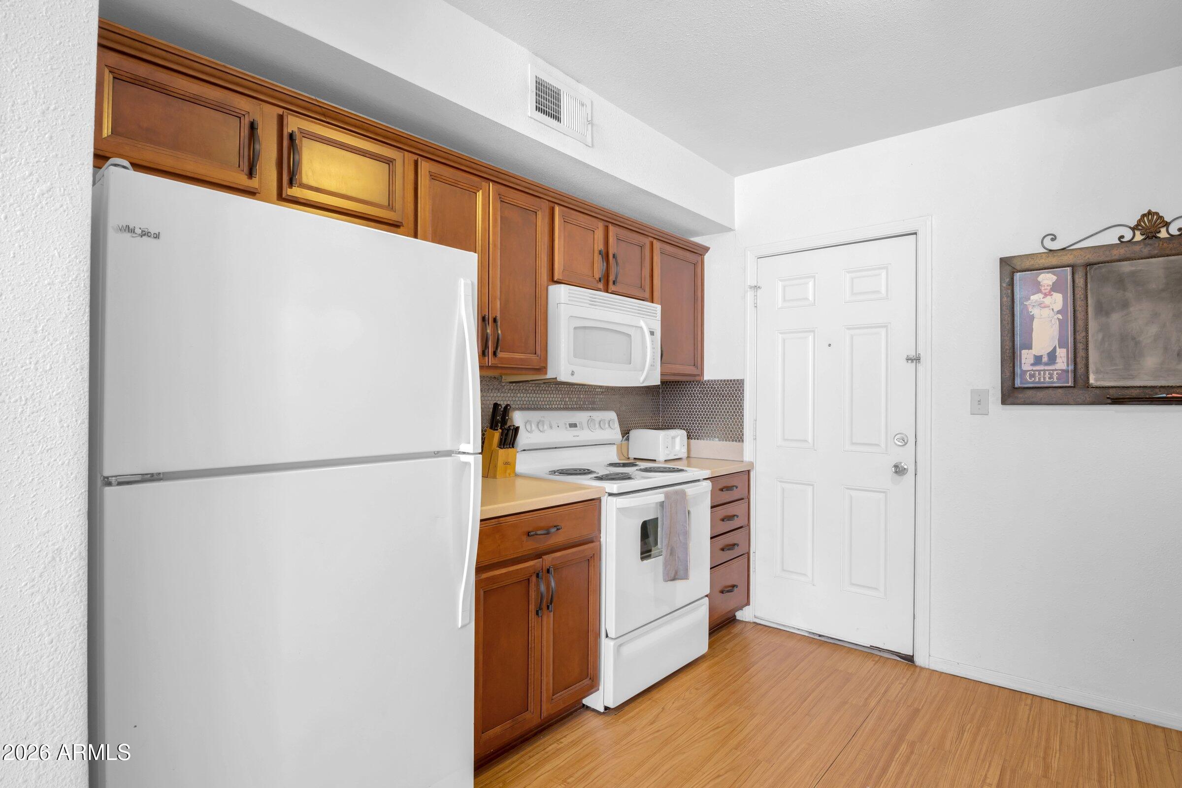 712 East Pierce Street Phoenix, AZ 85006 - Photo 36 of 39 a kitchen with a refrigerator a stove top oven a wooden floor and a window