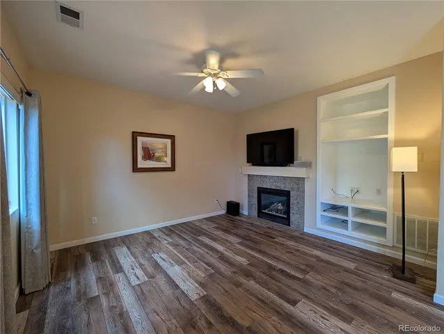 a view of a livingroom with a fireplace a ceiling fan and windows