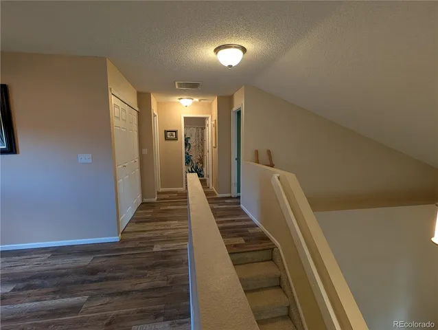 a view of a hallway with wooden floor and stairs