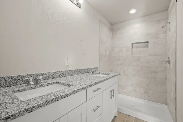 a bathroom with a granite countertop sink and a bathtub